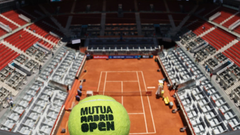 Imagen de la cancha del Mutua Madrid Open sin público y una pelota de tenis haciendo referencia al torneo.