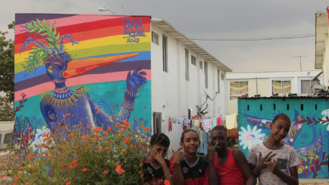 Niños del barrio Nuevo Ceibos saludan a la cámara, mientras que la obra de Carla Bresciani descansa detrás de ellos.