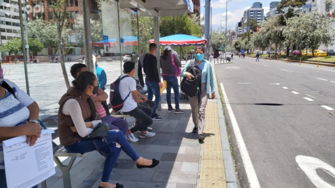 Personas esperan un bus sobre la avenida Amazonas de Quito, el 22 de septiembre de 2020.