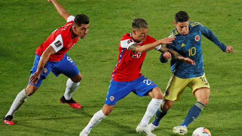 Charles Aranguiz (c) de Chile disputa un balón con James Rodríguez de Colombia durante el partido por las eliminatorias sudamericanas al Mundial de la FIFA Catar 2022 entre Chile y Colombia hoy, en el estadio Nacional, en Santiago (Chile). 