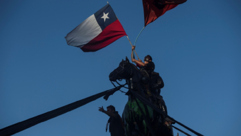 Manifestantes ondean banderas de Chile hoy, durante una toma de la Plaza Italia, en las horas previas al resultado del plebiscito constitucional, en Santiago (Chile), el 25 de octubre de 2020.