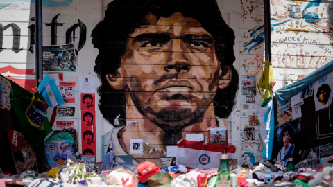 Imagen de ofrendas y figuras representativas en un mural de Diego Maradona convertido en santuario, en el Estadio de Argentinos Juniors.