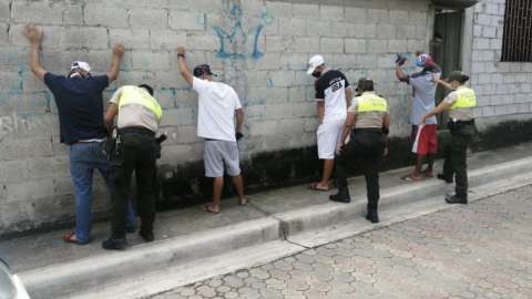 Personal de la Policía Nacional registrando a tres ciudadanos en la Florida, Guayaquil, durante el toque de queda.