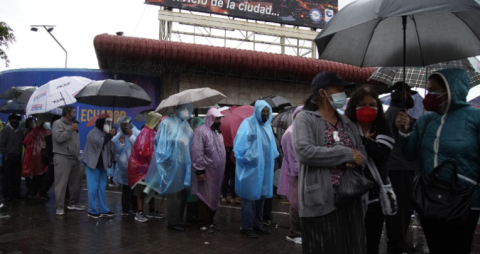 Adultos mayores esperan  ser vacunados, bajo la lluvia, en el Centro de Exposiciones Quito.