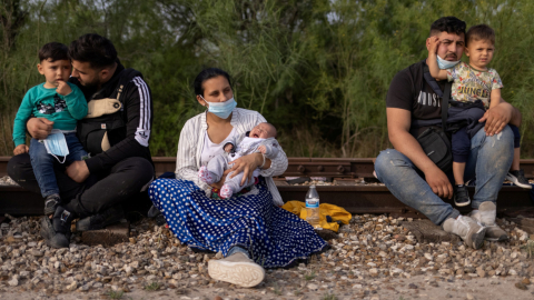 Migrantes rumanos en busca de asilo sostienen a sus hijos después de cruzar el río Grande hacia Estados Unidos desde México en una balsa en La Joya, Texas, Estados Unidos, 5 de mayo de 2021. 