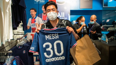 Un aficionado posa con la camiseta de Messi dentro de la tienda del PSG. 