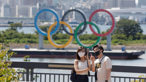 Una pareja se toma fotos frente a los anillos olímpicos, el 23 de julio de 2021.