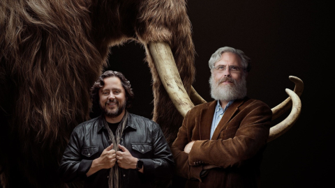 Fotografía cedida por la empresa Colossal donde aparecen sus cofundadores, los empresarios y científicos Ben Lamm (i) y George Church (d), mientras posan frente a la imagen de un mamut.