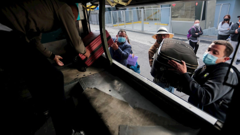 Venezolanos se suben a un bus que los llevara al aeropuerto Mariscal Sucre hoy viernes, frente al consulado de su país en Quito. 05 de noviembre de 2021