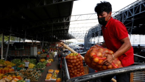 Un hombre descarga frutas de un camión de transporte en el mercado mayorista de Quito, el 10 de abril de 2021.