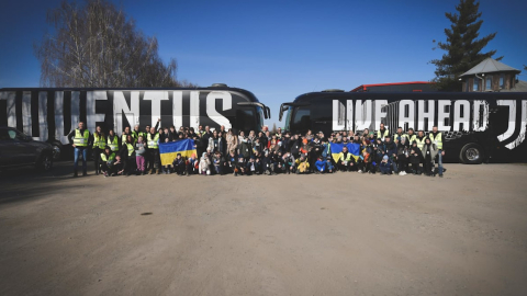 Las 80 personas rescatadas de Ucrania por la Juventus posan junto a buses del club, en Turín, el 12 de marzo de 2022.