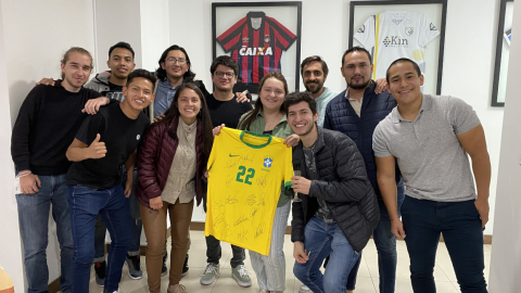 El equipo de Kin Analytics sostiene una camiseta de Brasil en sus oficinas en Quito.