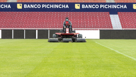 Un colaborador corta el césped del estadio Rodrigo Paz Delgado, propiedad de Liga de Quito.