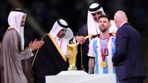 El príncipe Jassim bin Hamad bin Khalifa Al Thani aplaude mientras el emir de Qatar, el jeque Tamim bin Hamad Al Thani, le pone un Bisht a Lionel Messi de Argentina junto al presidente de la FIFA, Gianni Infantino durante la ceremonia de entrega de premios de la final del Mundial.