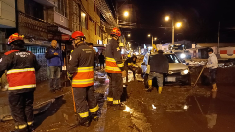 Bomberos retiraran el lodo en la calle principal de Guayllabamba, tras el desbordamiento, el 14 de enero de 2023. 