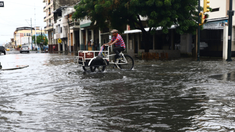 Una persona intenta cruzar una calle del sur de Guayaquil en su tricimoto, el 23 de abril de 2023.