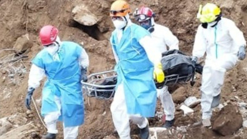 Rescatistas de Bomberos de Cuenca recuperan un cuerpo de la montaña de tierra en Alausí. 