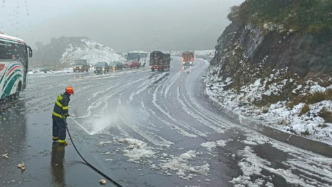 Un integrante del Cuerpo de Bomberos de Quito despeja la nieva de la vía a Papallacta.