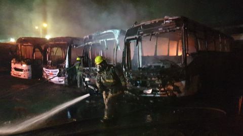 Un bombero de Guayaquil sofoca el incendio en un parqueadero de buses en el norte de la ciudad, el 16 de agosto de 2023.