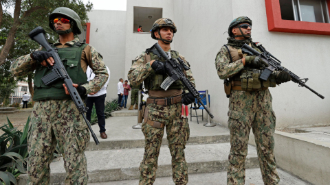 Tres militares fuertemente armados custodian un recinto electoral en Guayaquil, el 20 de agosto de 2023. 