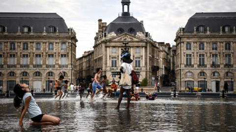 Los niños se refrescan mientras corren sobre una fina capa de agua en el Mirroir d'Eau a lo largo del río Garona, en Burdeos, suroeste de Francia, el 23 de agosto de 2023.