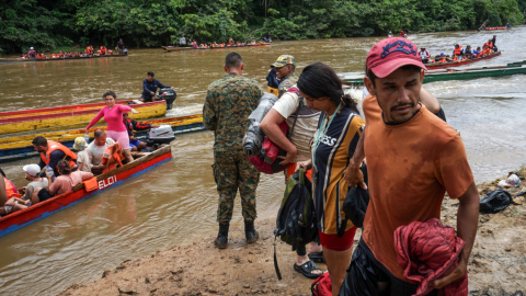 Un militar panameño recibe a un grupo de migrantes que cruza un río en la selva del Darién, el 18 de agosto de 2023. 