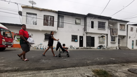 Una familia camina por la que fue la zona cero de la explosión de la Calle 8, en el Cristo del Consuelo en Guayaquil. Las fachadas de tres casas fueron reconstruidas. 