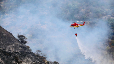 Un helicóptero del Cierpo de Bomberos de Quito realiza una descarga de agua en el sector de Itulcachi, el 1 de septiembre de 2023.