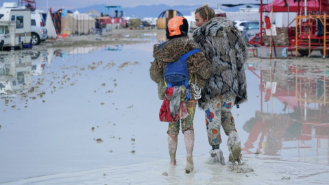 Dos personas caminan por el lodo del desierto de Nevada, luego de la lluvia que cayó sobre el festival Burning Man.