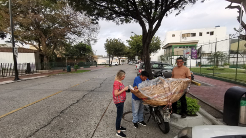 Miembros del Comité  Los Ceibos adquieren pan en una venta ambulante frente a la sede de la asociación barrial en el norte de Guayaquil. 