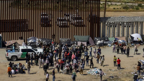 Fotografía general donde se observa a migrantes en un campamento junto al muro fronterizo, en Tijuana, Baja California (México).