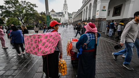 Dos mujeres indígenas venden frutas en el centro de Quito, el 15 de agosto de 2023. 