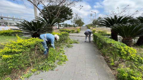 Dos trabajadores limpian la maleza en el parque Samanes, norte de Guayaquil, el  21 de septiembre de 2023.