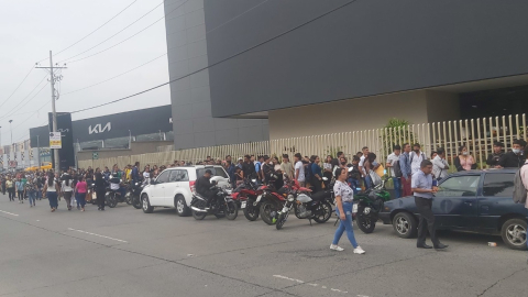 Personas hacen una columna en los exteriores de un centro comercial durante una convocatoria laboral, en Guayaquil, el 12 de octubre de 2023. 