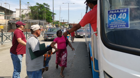 Una madre con su hija se apresuran a abordar un bus con un adhesivo de la tarifa de USD 0,40, que buscan imponer transportistas en Guayaquil. 