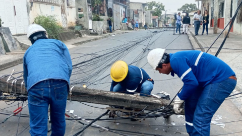 Tres técnicos de CNEL EP arreglan un poste de luz en Guayaquil, el 6 de noviembre de 2023.