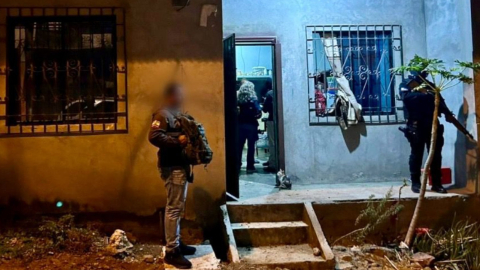 Dos policías en los exteriores de una vivienda allanada, durante la captura de 12 sujetos en Guayaquil, el 30 de noviembre de 2023.