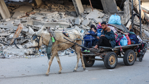 Un hombre junto a un niño abandonan un campo de refugiados en el centro de Gaza, tra una nueva orden de evacuación por bombardeos de Israel, el 22 de diciembre de 2023.