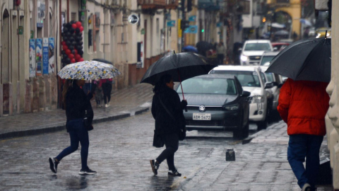 Personas caminan bajo la lluvia en el centro de Cuenca el 23 de noviembre de 2023.