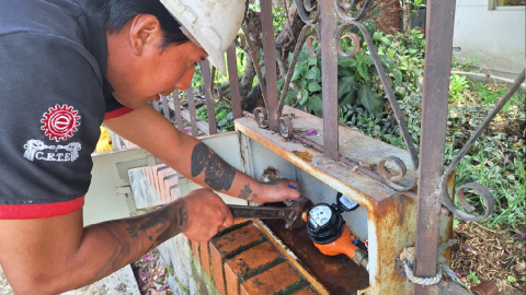 Un funcionario de la empresa de agua potable de Cuenca instala un medidor.