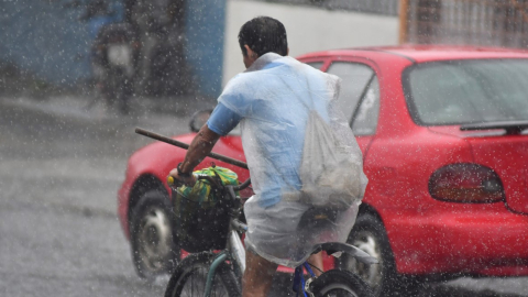 Imagen referencial de un ciclista protegiéndose de la lluvia con un plástico.  En cinco provincias de la Costa se prevén lluvias de nivel alto y muy alto.