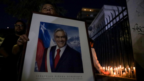 Una mujer sostiene un retrato del fallecido expresidente, Sebastián Piñera, en los exteriores del palacio de gobierno en Santiago de Chile, el 6 de febrero de 2024.