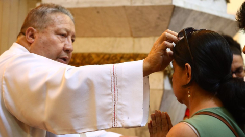 Un sacerdote impone la ceniza a feligreses de la iglesia San Francisco, en Guayaquil.