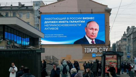 La gente pasa junto a un enorme cartel digital que muestra al presidente y candidato presidencial ruso Vladimir Putin, en San Petersburgo, Rusia, el 14 de marzo de 2024.