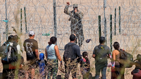 Migrantes hablan con un agente de la Guardia Nacional de Texas después de cruzar el río Grande en Ciudad Juárez, en México, el 13 de marzo de 2024.