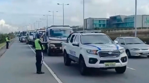 Agentes de tránsito custodian a grúas con vehículos retenidos en las inmediaciones del Aeropuerto de Quito.