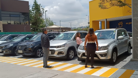 Un asesor de una agencia de 1001Carros muestra los carros que tiene la agencia a dos visitantes. Foto del 28 de marzo de 2024. 