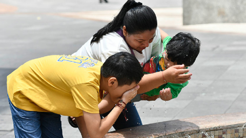 Una mujer y sus hijos en una fuente de agua en el centro de Guayaquil.