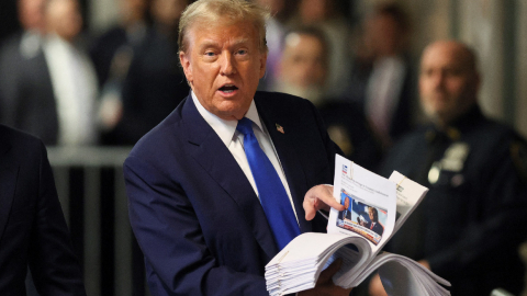 presidente estadounidense Donald Trump sostiene recortes de prensa mientras habla con la prensa al concluir el tercer día de su juicio por supuestamente encubrir pagos de dinero vinculados a relaciones extramatrimoniales en el Tribunal Penal de Manhattan en Nueva York el 18 de abril de 2024.