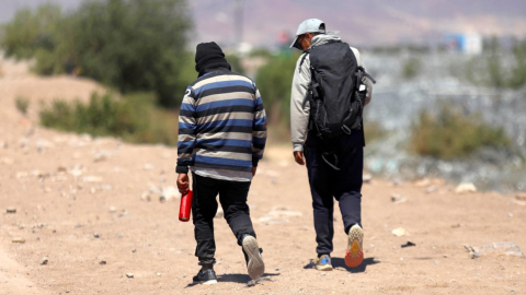 Los migrantes ecuatorianos Luis Hernández Saldaña (40) y Javier Villareal (45) caminan por las orillas del Río Bravo en busca de una brecha para cruzar a Estados Unidos desde Ciudad Juárez, en México.